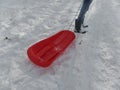 Girl in jeans and wellington boots pulling a red sledge in the snow Royalty Free Stock Photo
