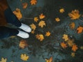 Girl with jeans and white sneakers stands in the autumn in yellow leaves Royalty Free Stock Photo