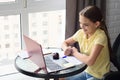 Girl joyfully looks at the laptop screen while sitting at a table in the apartment and doing homework