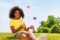 Girl juggle with balls on the lawn in park smiling