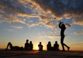 Girl juggling poi balls, sunset with colorfull clouds background