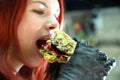 Girl with a juicy burger. Close up portrait of a smiling hungry young woman eating burger.