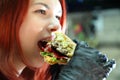 Girl with a juicy burger. Close up portrait of a smiling hungry young woman eating burger.