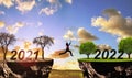 Girl jumping from arid land with number 2021 on lush landscape with number 2022. Concept of Happy New Year.