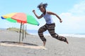 Girl jumping on beach by parasol