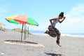 Girl jumping on beach by parasol