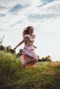 girl jumping in the field in a pink dress