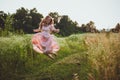 girl jumping in the field in a pink dress