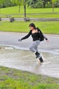 Girl jumping through flood on road