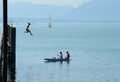 Girl jumping from high pier to water and two other on kayak
