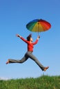 Girl jumping over grass with colorful umbrella Royalty Free Stock Photo