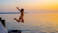 Girl jumping from pier in the water at sunset Royalty Free Stock Photo