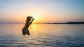 Girl jumping from pier in the water at sunset Royalty Free Stock Photo