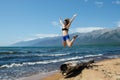 Girl jumping from very old wooden rotten log aground on the beach, near lake Baikal, Russia, on a sunny day in the Royalty Free Stock Photo