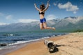 Girl jumping from very old wooden rotten log aground on the beach, near lake Baikal, Russia, on a sunny day in the Royalty Free Stock Photo