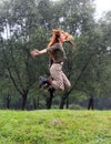 Girl jumps on a grass and trees as a background Royalty Free Stock Photo