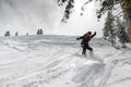 girl jumps with a snowboard from a hill, a springboard with snow, in the mountains against the background of trees Royalty Free Stock Photo