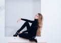 Girl just want to have fun. Lady long hair black tights high heels looks bored. Girl hairstyle skinny sit niche wall