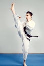 girl in karate suit kimono in studio at grey background. Female child shows judo or karate stans in white uniform with black belt. Royalty Free Stock Photo