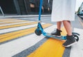 The girl on the electric kick scooter at a pedestrian crossing, legs close-up