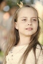 Girl kid on calm face with tiny golden crown on head, nature background, defocused. Girl princess with little crown