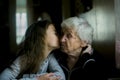 A girl kisses her great-grandmother while visiting her. Royalty Free Stock Photo