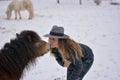 The girl kisses her horse under a heavy winter snowfall Royalty Free Stock Photo