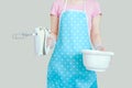 Girl in the kitchen apron is holding a mixer and a bowl. Gray background