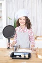 Girl in kitchen. Little cook. Large black frying pan. Cooking pr