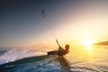 girl kiter rides against a beautiful background of splashes and a colorful sunset of the sea. Woman kitesurfing on the Royalty Free Stock Photo