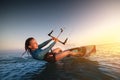 Girl kitesurfing in a sexy hydrosuit with a kite in the sky on board in the blue sea, riding on the water waves Royalty Free Stock Photo