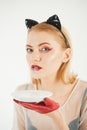 Girl in kitten ears and red gloves with yoghurt isolated on white. cat woman lick milk from plate. Food and drink Royalty Free Stock Photo