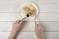 A girl with a knife and fork, cuts a piece of apple strudel with ice cream on white wooden table Royalty Free Stock Photo