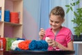 Girl knits a soft toy sitting at a table in the interior of a childrenÃ¢â¬â¢s room