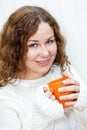 Girl in knitted sweater enjoying a cup of hot tea in hands, portrait of curly woman on white Royalty Free Stock Photo