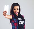 This girl knows how to have fun. a trendy young woman taking a selfie against a gray background.