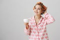 Girl knows she will be fabulous at party. Indoor shot of attractive female student at dormitory, wearing hair curlers