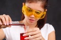 A girl lab assistant pouring liquid from a test tube into a flask close-up on a black background