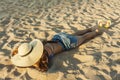 Girl laid on the beach wearing beach summer hat