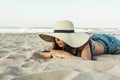 Girl laid on the beach wearing beach summer hat