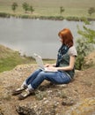 Girl with laptop at rock near lake and tree. Royalty Free Stock Photo