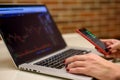 Girl with laptop and smartphone watching bitcoin graphs and stocks Royalty Free Stock Photo