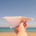 A girl is launching a paper airplane on the sunset beach. Travel and summer concept. Royalty Free Stock Photo