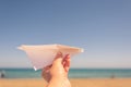 A girl is launching a paper airplane on the sunset beach. Travel and summer concept. Royalty Free Stock Photo