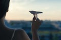 A girl is launching a paper airplane from a window at sunset. Royalty Free Stock Photo
