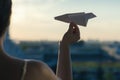 A girl is launching a paper airplane from a window at sunset. Royalty Free Stock Photo