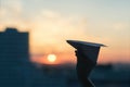 A girl is launching a paper airplane from a window at sunset. Royalty Free Stock Photo