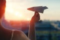 A girl is launching a paper airplane from a window at sunset. Support of the Telegram application and freedom internet. Royalty Free Stock Photo