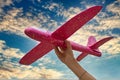 Girl launching a pink toy plane into the air against the sky background