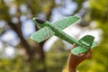 Girl launching toy airplane against green garden and sky, evening lighting.